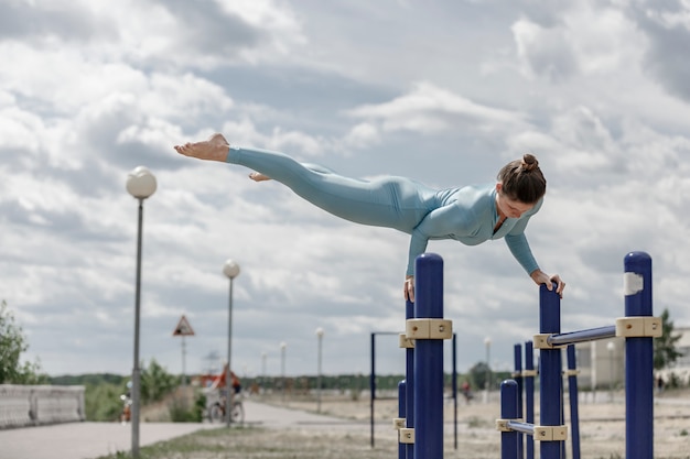 Foto acrobaatmeisje in een blauw kostuum op een rekstok