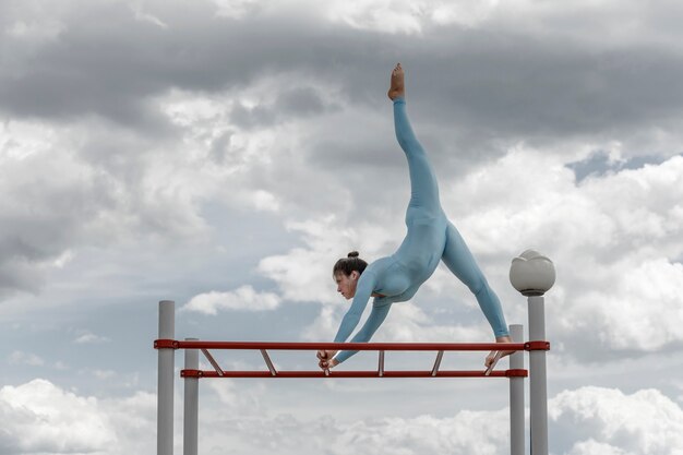 Acrobaatmeisje in een blauw kostuum op een rekstok