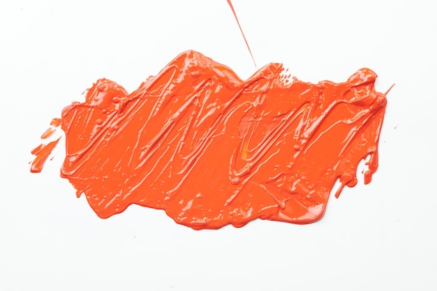 Photo acrylic paint blot chaotic brushstroke spot flowing on white paper background creative orange color backdrop fluid art