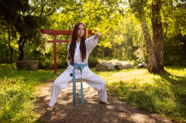 actief meisje in witte kimono met blauwe riem die vechtsportvaardigheden uitvoert