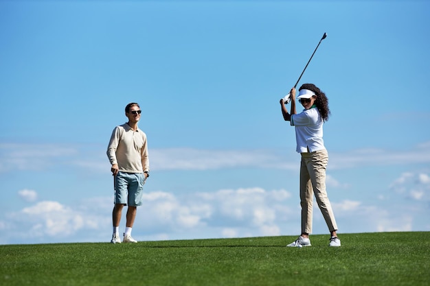 Actief paar golfen tegen de blauwe lucht met swingende golfclub