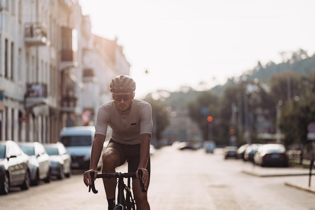 Actieve blanke man in veiligheidshelm en gespiegelde bril oefenen in fietsen op straat in de stad Professionele wielrenner die vrije tijd doorbrengt voor regelmatige training