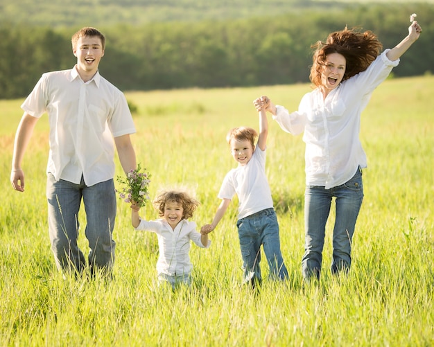 Actieve gelukkige familie die buiten springt in het groene lenteveld