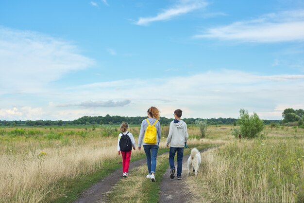 Actieve gezonde levensstijl, kinderen buiten met hond, familie jongen en meisjes wandelen langs landweg, achteraanzicht