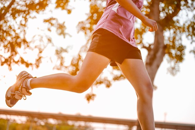 Actieve gezonde loper joggen buiten. Vrouw joggen in het park in zonsopganglicht