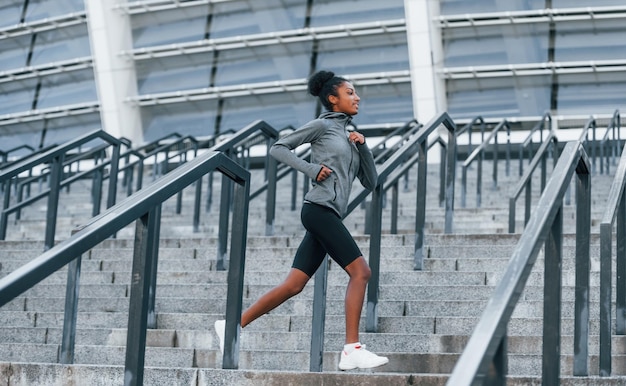 Actieve hardloper Jonge Afro-Amerikaanse vrouw in sportieve kleding traint overdag buiten