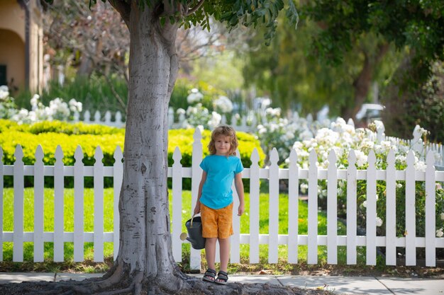 Actieve jongen die planten water geeft op achtertuin concept van plant groeiende leeractiviteit voor schoolkind...