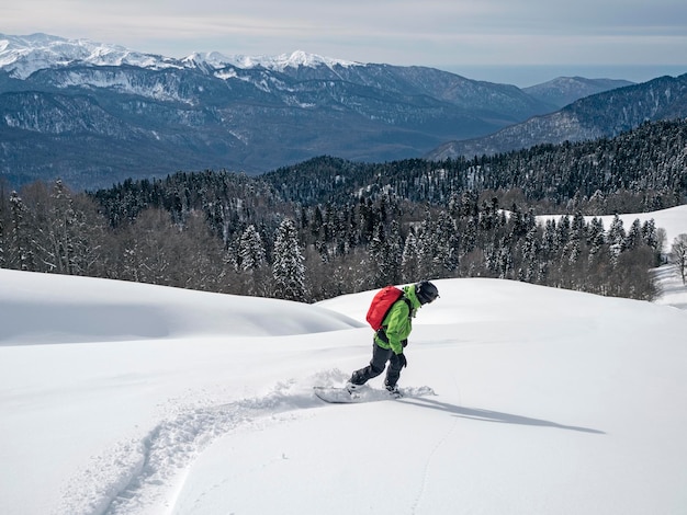 Actieve man snowboard rijden op poedersneeuw op bergen bos en zee achtergrond in Krasnaya Polyana Rusland