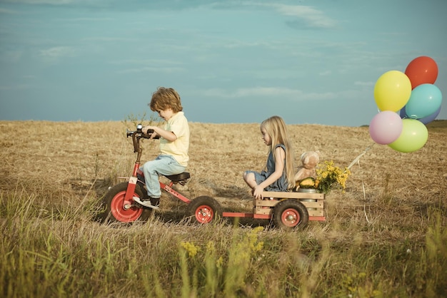 Actieve peuter jongen spelen en buiten fietsen Kinderen boer op de boerderij met landelijke achtergrond Schattige peuter meisje en jongen werken op de boerderij buitenshuis Kinderen genieten op boerderij aarde dag