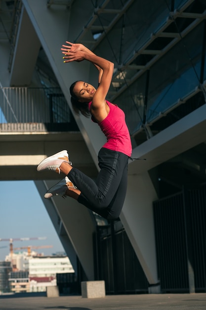 Actieve professionele sportvrouw die hoog springt tijdens buitentraining