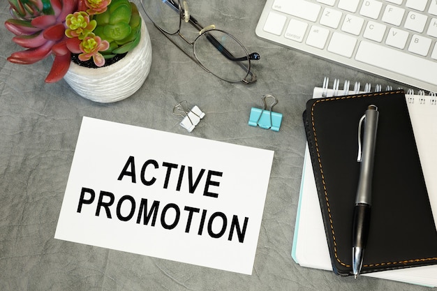 Actieve promotie - belettering op papier op het bureaublad, notitieblok, pen en toetsenbord. Conceptfoto van het voordeel.