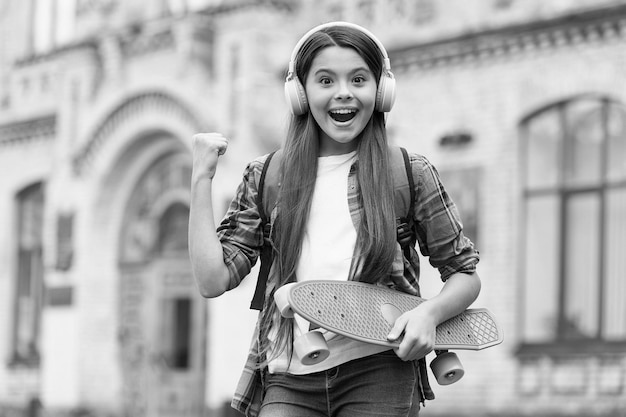 Actieve rit Gelukkig meisje skater flex arm met penny board buitenshuis Actie sport Recreatieve activiteit Gezonde levensstijl Straat skateboarden Zomervakantie Actief en energiek