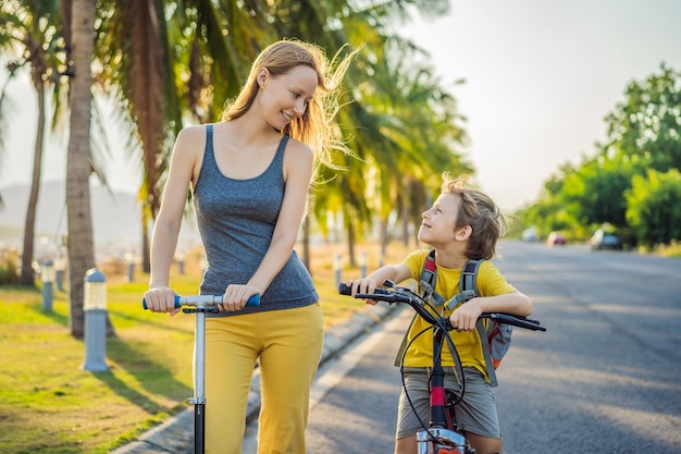 Actieve school jongen jongen en zijn moeder fietsen met rugzak op zonnige dag Gelukkig kind fietsen op weg naar school Veilige manier voor kinderen buiten naar school