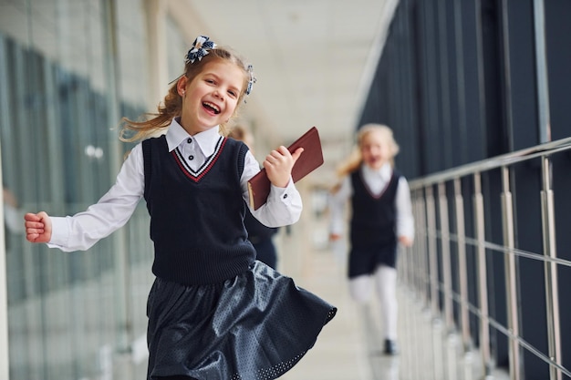 Actieve schoolkinderen in uniform lopen samen in gang Conceptie van onderwijs