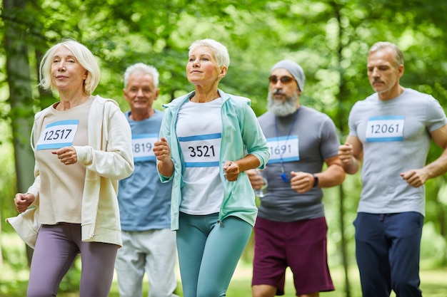 Actieve senior mannen en vrouwen zomertijd samen doorbrengen in park met marathon, middellange afstandsschot