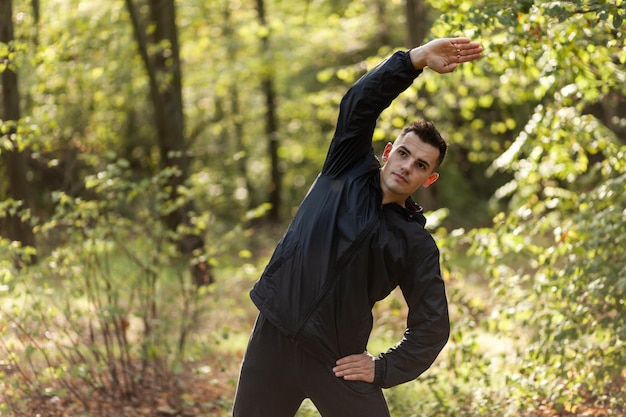 Actieve sportman traint opwarmingsoefeningen of rekoefeningen in het herfstbos Gezonde levensstijl Outdoor workout