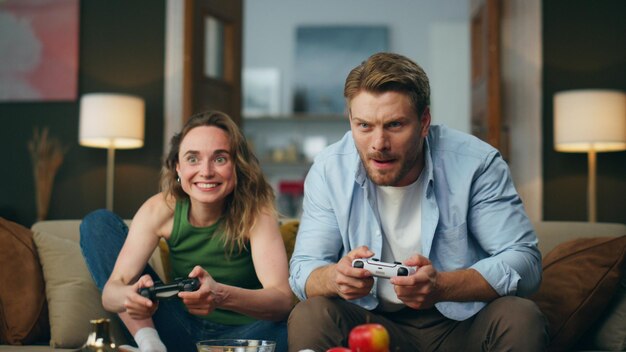 Actieve vrienden spelen console game comfortabel huis opgewonden paar probeert te winnen