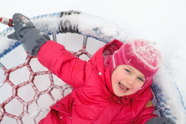 Actieve vrijetijdskinderen buitenshuis in de wintersneeuw Gelukkig opgewonden kind in de speeltuin