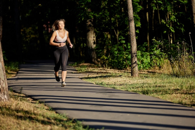 Actieve vrouw rent in het openbare park op zomerdag