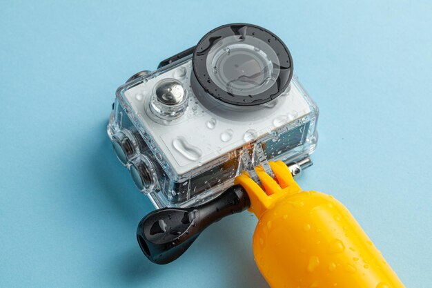 Action camera in a waterproof box and a buoy for diving in water drops on a blue background.