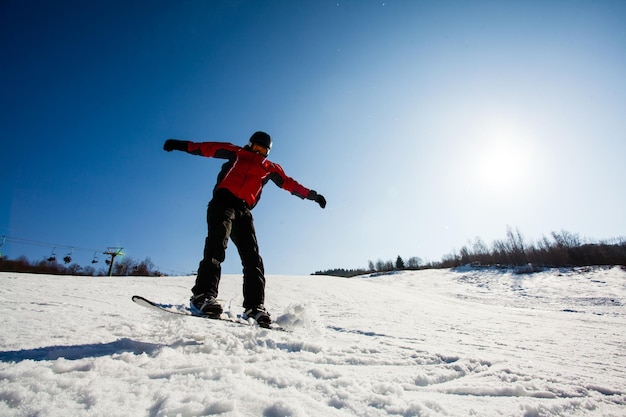 Action photo of professional snowboarder riding down the hill on sunny frosty day