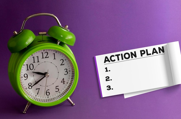 Action Plan numbered 1 2 3 writing on a notepad notepad on purple background with a green table clock