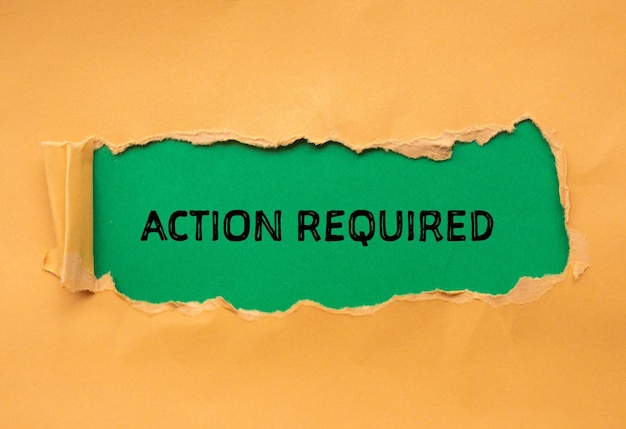 Action required words written on orange torn paper with green background