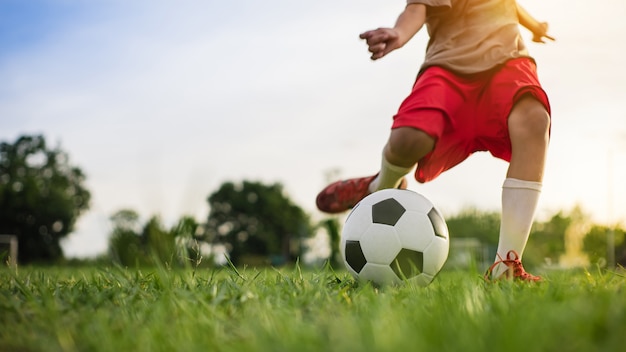 Экшн-спорт на открытом воздухе мальчиков, весело играя в футбол для упражнений.