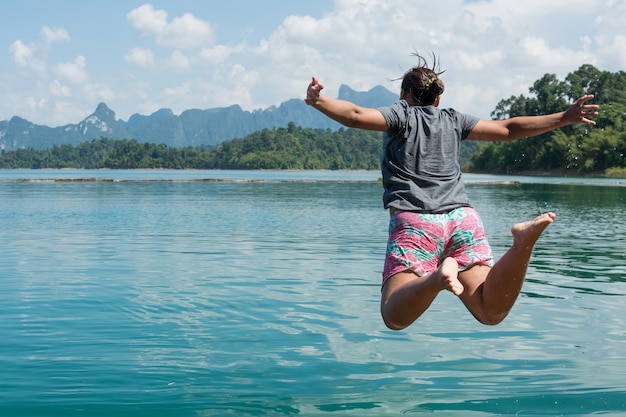 Action of young woman jumping into a lake