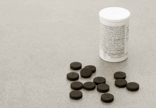 Activated Charcoal Tablets For cleansing the Body dumped On the Grey Background.