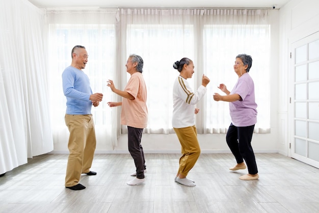 Active Asian senior group mix with man and woman exercise by dancing together at home with relaxing