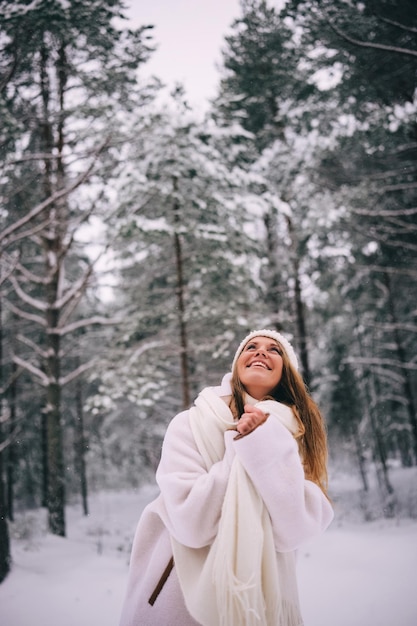 Active beautiful young woman in white clothes enjoying snowy winter forest