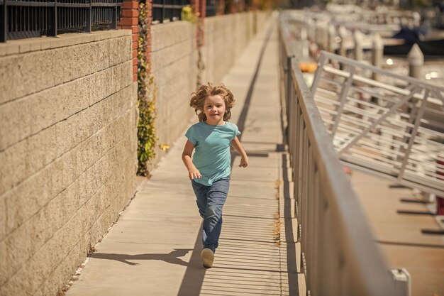 アクティブな男の子の子供は夏の活動で遊歩道を走ることを楽しんでいます