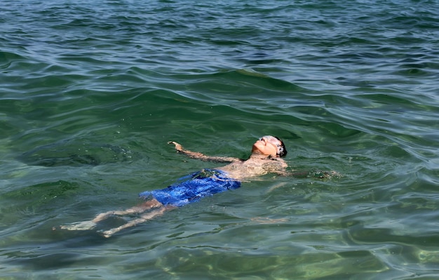 Активный мальчик плавает в морской воде.