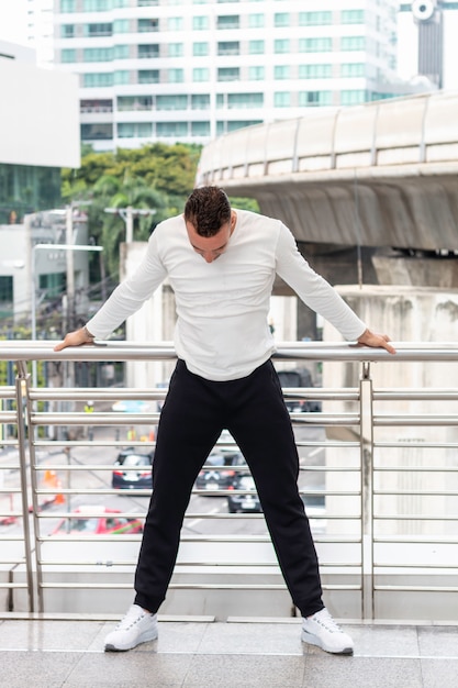 Active Caucasian young man tired and resting during exercise on street outdoor.