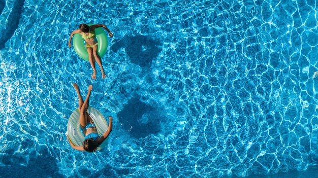 Bambini attivi in piscina vista aerea dall'alto dall'alto, bambini felici nuotano su ciambelle gonfiabili e si divertono in acqua in vacanza con la famiglia in vacanza sul resort