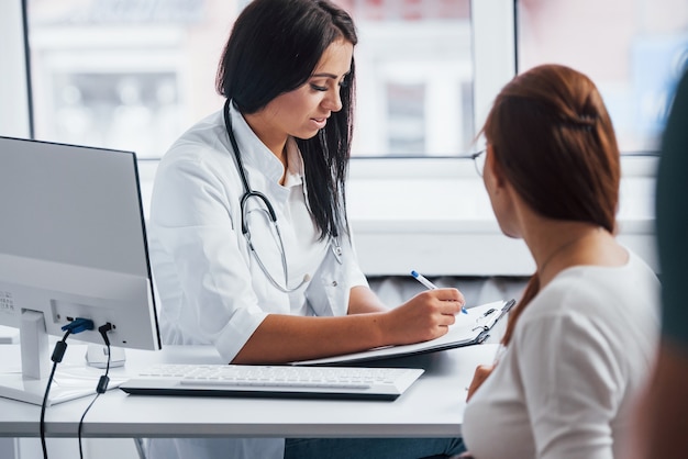 Active conversation. Pregnant woman have consultation with obstetrician indoors.