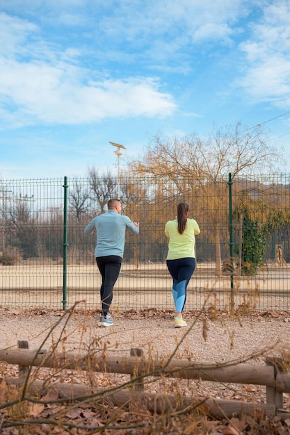 Photo active couple in athletic wear stretching together outdoors