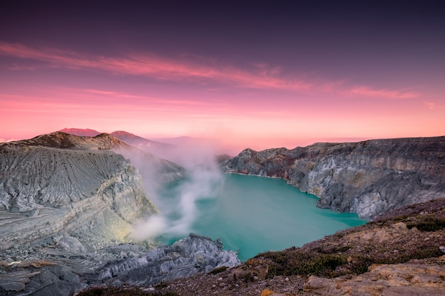 朝のカラフルな空とターコイズブルーの湖の硫黄の煙で活動的な火口火山