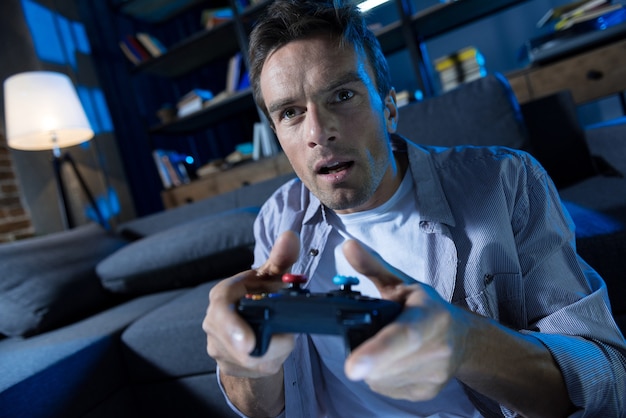 Active determined young guy spending the evening in front of the screen playing a game and completing levels