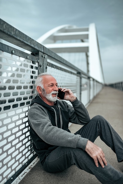 Активный пожилой мужчина отдыхает и разговаривает по телефону.