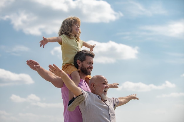 Active family leisure with kids boy son with father and grandfather raising hands or open arms flyin...