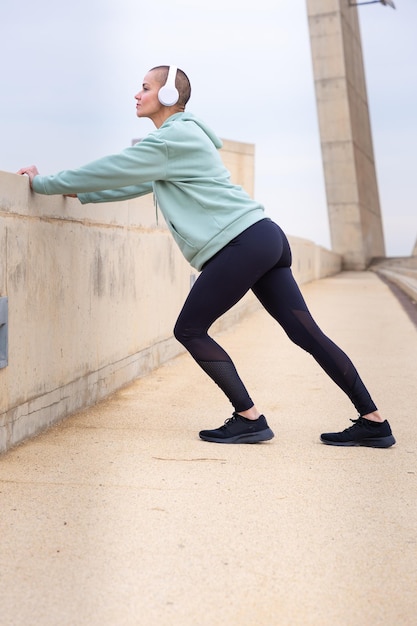 Active and fit female runner in warmup stretching for running or cardio exercise vertical