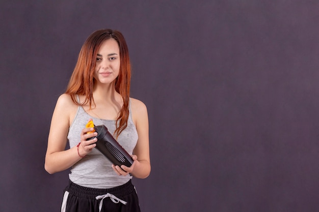 La ragazza attiva dopo il jogging beve l'acqua