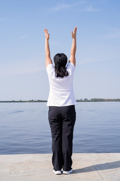 Active and happy senior woman exercising near the riverside