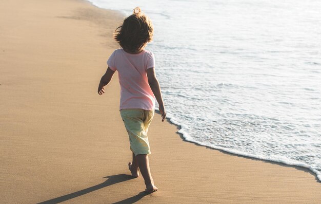 夏休みを楽しんでいるアクティブな子供砂浜で走っている子供の男の子