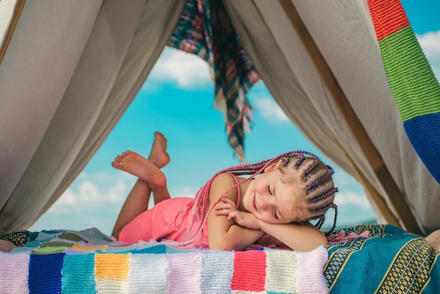 Active kid lifestyle Smiling child in tent Girl playing in camp Outdoor camping and having fun at campground