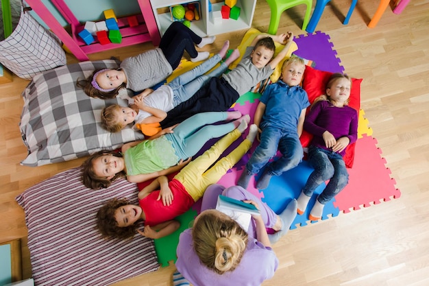 幼稚園で柔らかい枕やマットの上に横たわっているアクティブな子供たち