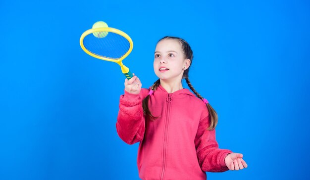 Active leisure and hobby Tennis sport and entertainment Girl adorable child play tennis Practicing tennis skills and having fun Great day to play Athlete kid tennis racket on blue background