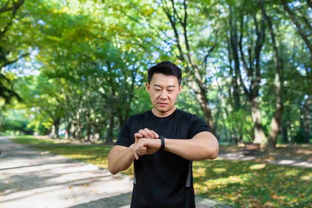 활동적인 라이프스타일 현대 기술 젊은 스포티 아시아 남자는 피트니스 팔찌를 사용하여 스마트하게 보입니다.